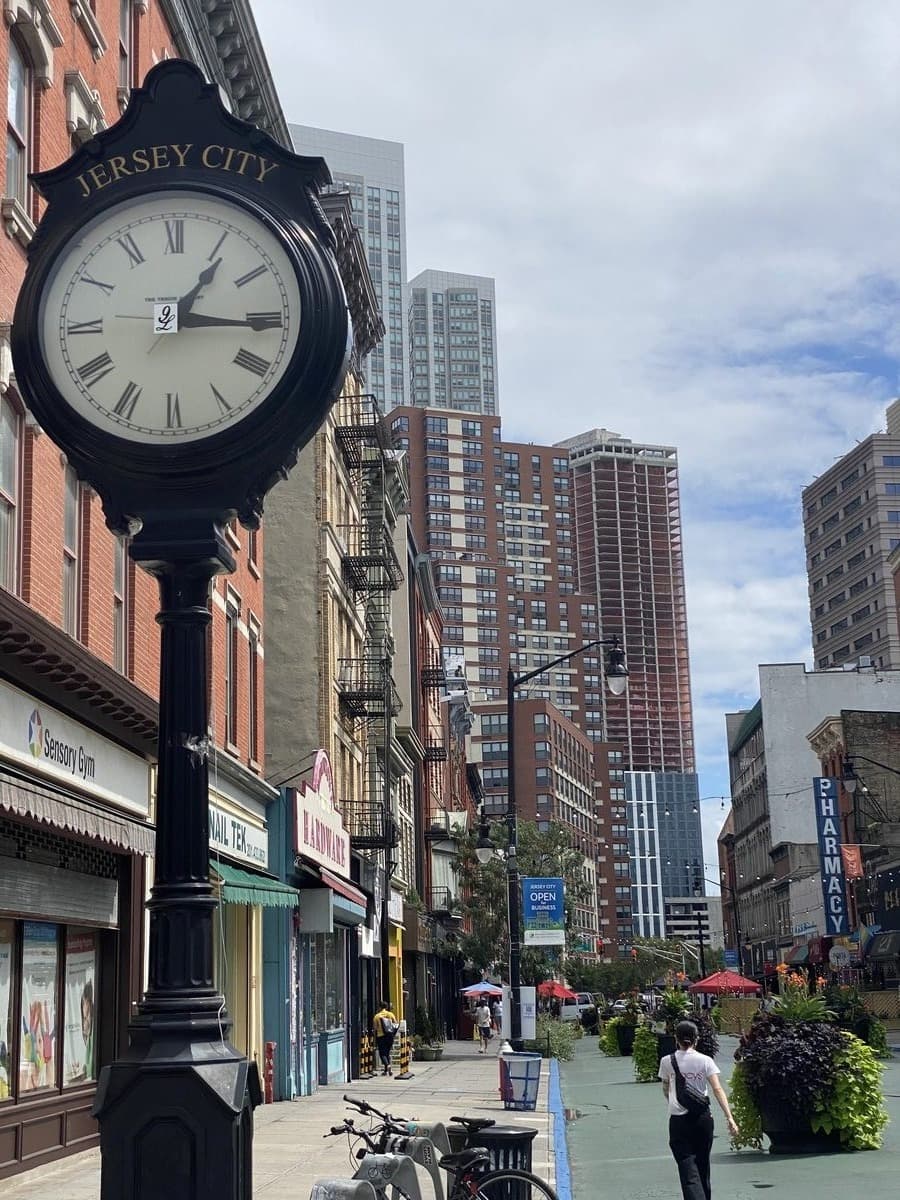 Reloj de calle en Jersey City con el skyline al fondo — carácter de barrio Hudson